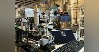 AlgaeBarn in-house cap labeling cell with label spool and vision quality counters
